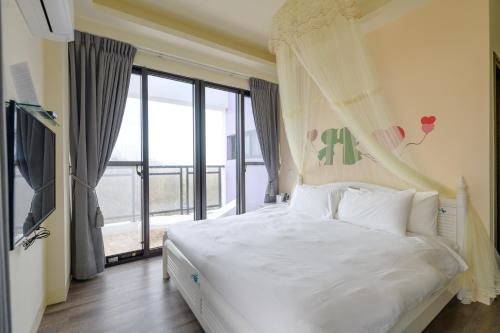 1 dormitorio con cama blanca y ventana grande en Fengxianlu Herb Garden Homestay, en Magong