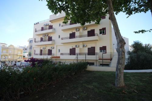 a building with balconies and a tree in front of it at Hospedaria Buganvilia Alvor in Alvor