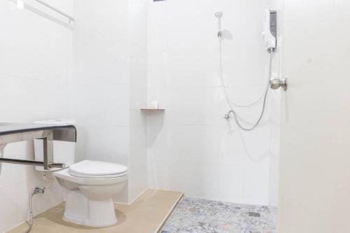 a white bathroom with a toilet and a shower at Yaibua Hotel in Ban Chamun (2)