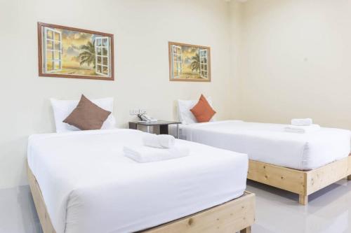 two beds in a room with white walls at Yaibua Hotel in Ban Chamun (2)