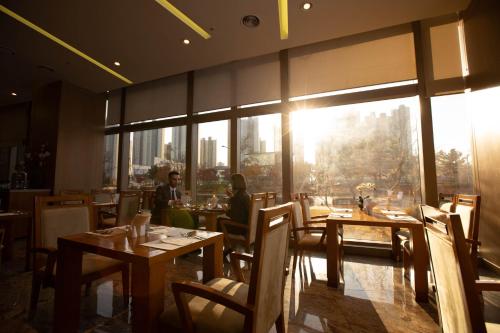 a dining room with tables and chairs and a large window at Songdo Central Park Hotel in Incheon