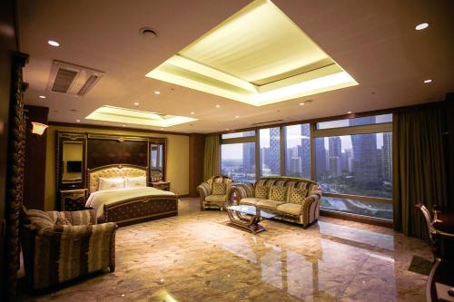 ein Schlafzimmer mit einem Bett und Stühlen sowie einem großen Fenster in der Unterkunft Songdo Central Park Hotel in Incheon