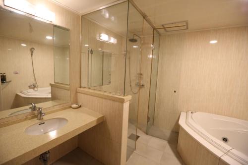 a bathroom with a sink and a shower and a tub at Symphony Hotel in Suwon