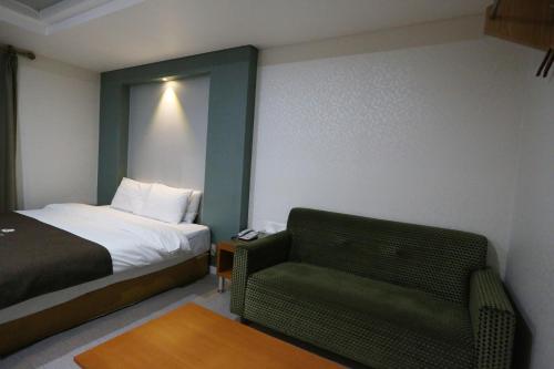a hotel room with a bed and a chair at Symphony Hotel in Suwon