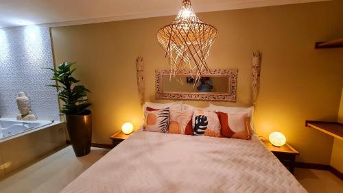 a bedroom with a bed and a chandelier at Pousada Paraíso Gaia in Praia do Rosa