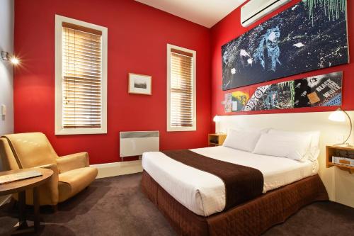 a red bedroom with a bed and a chair at Tolarno Hotel in Melbourne