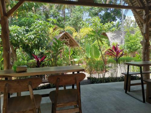 a patio with tables and chairs in a garden at Coconut Tree Cottages in Batukaras