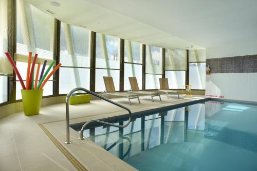 - une piscine avec une rangée de chaises à côté de la piscine dans l'établissement Domitys Le Jardin des Trois Rois, à Romorantin-Lanthenay