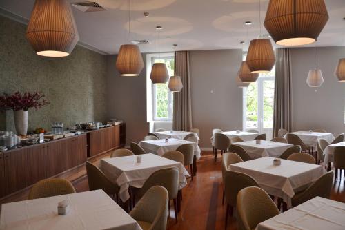 a restaurant with white tables and chairs and a counter at Hotel do Parque in Braga