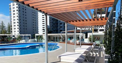 uma piscina com espreguiçadeiras ao lado de um edifício em ULTIQA Beach Haven on Broadbeach em Gold Coast