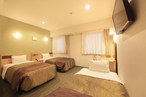 a hotel room with two beds and a television at Hotel Grand City in Tokyo