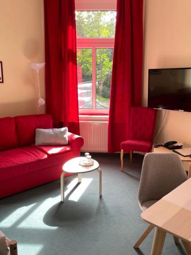 a living room with a red couch and a window at Parkhotel Schnorr in Lutherstadt Eisleben