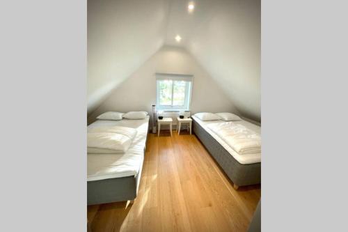 1 dormitorio en el ático con 2 camas y ventana en Eget hus med bra läge och toppstandard, en Linköping