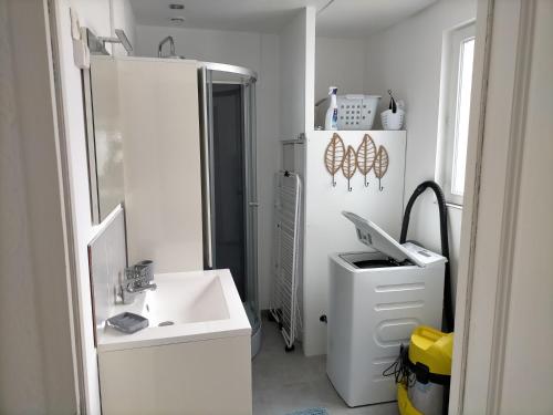 ein weißes Badezimmer mit einem Waschbecken und einem Spiegel in der Unterkunft Gîte Cœur d'Opale, seul hébergement 4 étoiles sur Étaples in Étaples