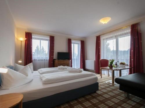 una habitación de hotel con una cama grande con cortinas rojas en Hotel Kühbergalp, en Gunzesried