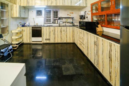 a kitchen with wooden cabinets and a black floor at Belljem Homes -your own private resort -6 BHK S in Trichūr