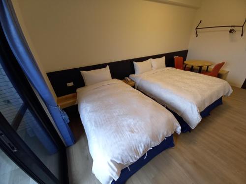 two beds sitting next to each other in a room at 航空棧輕旅民宿 in Huxi