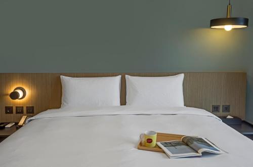 a bed with a tray with a book and a cup on it at Hotelday Sun Moon Lake in Yuchi