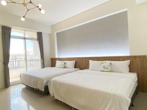 two beds in a bedroom with a large window at Kun Inn - Nandao in Taitung City