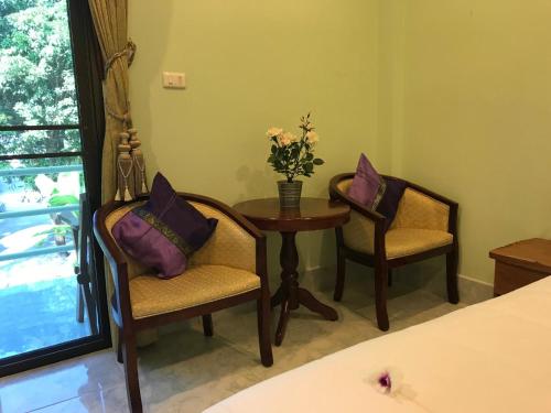 a room with two chairs and a table with a vase of flowers at Kasemsuk Guesthouse SHA Extra plus in Karon Beach