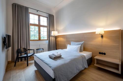um quarto de hotel com uma cama e uma cadeira em Kloster Seeon em Seeon-Seebruck