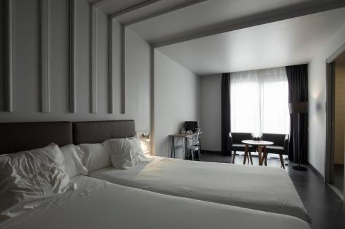 a bedroom with a large white bed and a table at Hotel Lux Santiago in Santiago de Compostela