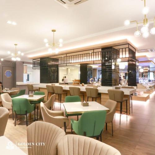 a restaurant with tables and chairs and a bar at Golden City Rayong Hotel in Rayong