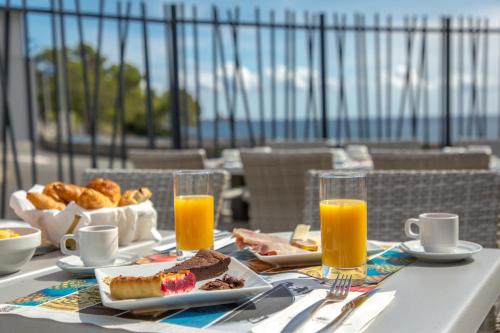 una mesa con desayuno y zumo de naranja en el balcón en SOWELL Family Riviera, en Saint-Raphaël