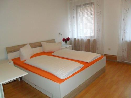a bedroom with an orange and white bed and a window at Hotel Hirsch in Seebach