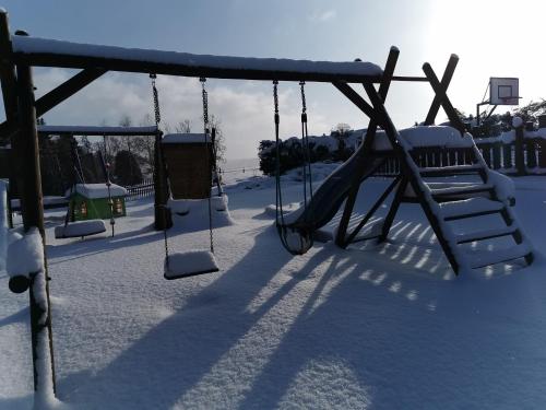 a swing set in a playground covered in snow at Apartmány Dolní Moravice in Dolní Moravice