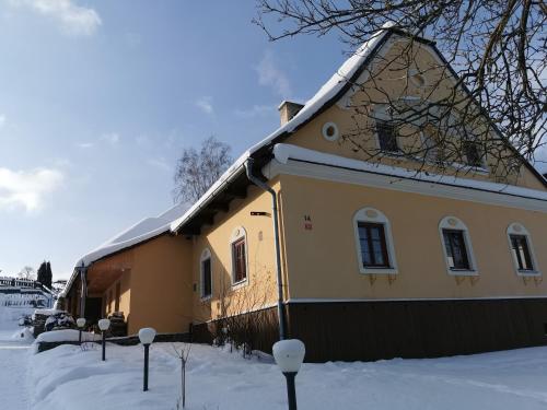 a yellow house with a snow covered roof at Apartmány Dolní Moravice in Dolní Moravice