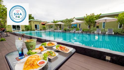 a table with plates of food next to a swimming pool at Sky Hip Resort - SHA Certified in Jomtien Beach