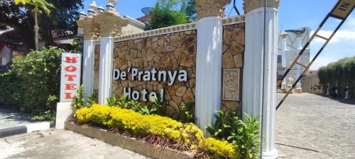a stone wall with a sign for a hotel at Votel Hotel De'Pratnya Kediri in Kediri