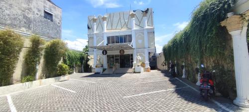 a building with a motorcycle parked in front of it at Votel Hotel De'Pratnya Kediri in Kediri