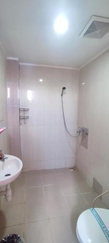 a bathroom with a shower and a toilet and a sink at Votel Hotel De'Pratnya Kediri in Kediri