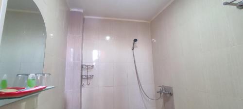 a white bathroom with a shower with a shower at Votel Hotel De'Pratnya Kediri in Kediri