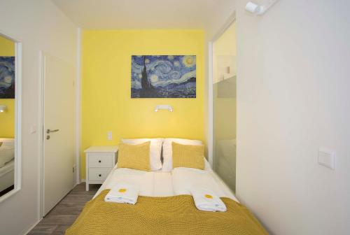 a small bedroom with a bed with yellow walls at Zentral gelegene, helle Studio Apartments in Nürnberg