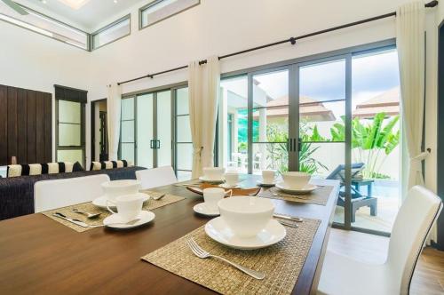 a dining room with a table with white dishes on it at Shanti Villas x MonthStayZ Thailand in Rawai Beach