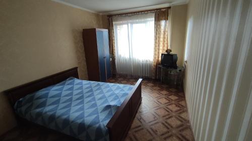a bedroom with a blue bed and a window at 1-ная квартира по адресу Глушко 28 in Odesa