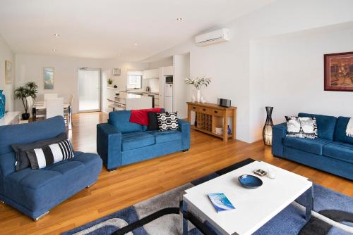 a living room with two blue couches and a table at Fairview - Margaret River in Margaret River Town