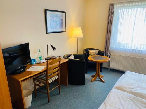 a hotel room with a desk and a bed and a room at Hotel Alte Mühle in Elsfleth