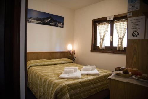 リモーネ・ピエモンテにあるHotel Marguareisのタオルが敷かれたベッドのある寝室