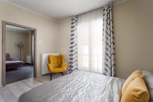 エゲルにあるImpulse apartmanのベッドルーム1室(ベッド1台、黄色い椅子付)