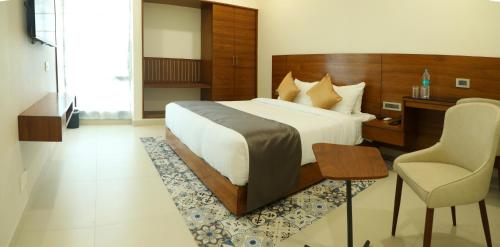 a bedroom with a bed and a desk and a chair at GG HOTELS in Tiruppūr