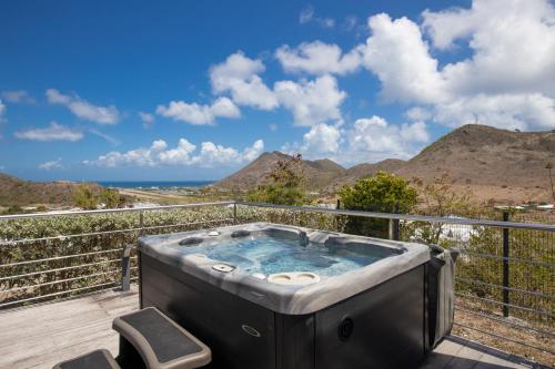 a hot tub on a deck with mountains in the background at The Rock in Cul de Sac