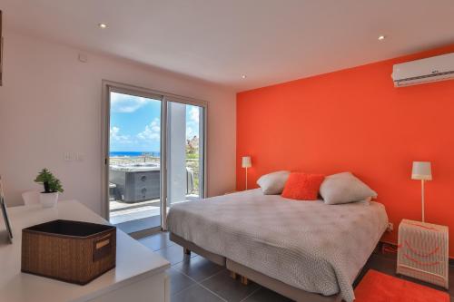 a bedroom with an orange wall with a bed and a window at The Rock in Cul de Sac