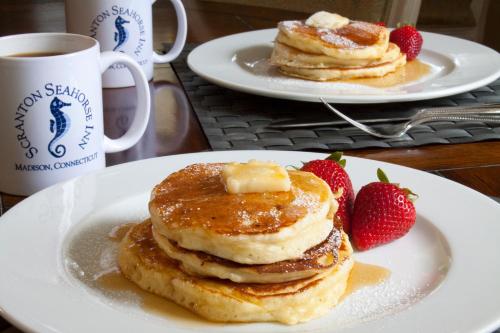 two plates of pancakes with strawberries on a table at Scranton Seahorse Inn in Madison