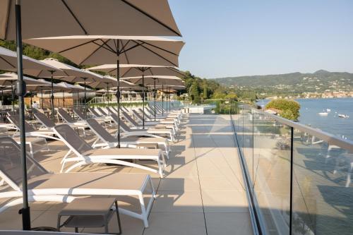 a row of lounge chairs with umbrellas on a balcony at Ah Porticcioli Boutique Apartments in San Felice del Benaco