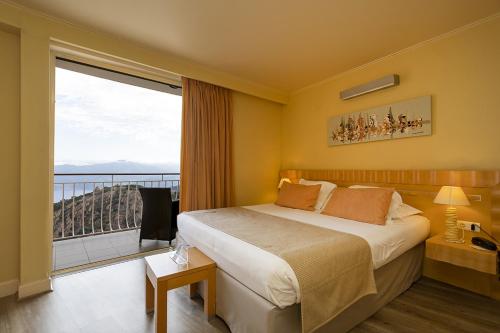 una camera d'albergo con un letto e una grande finestra di Hôtel Capo Rosso a Piana