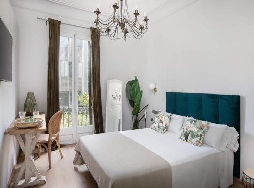 1 dormitorio con cama, mesa y lámpara de araña en La Maison de Barcelone, en Barcelona